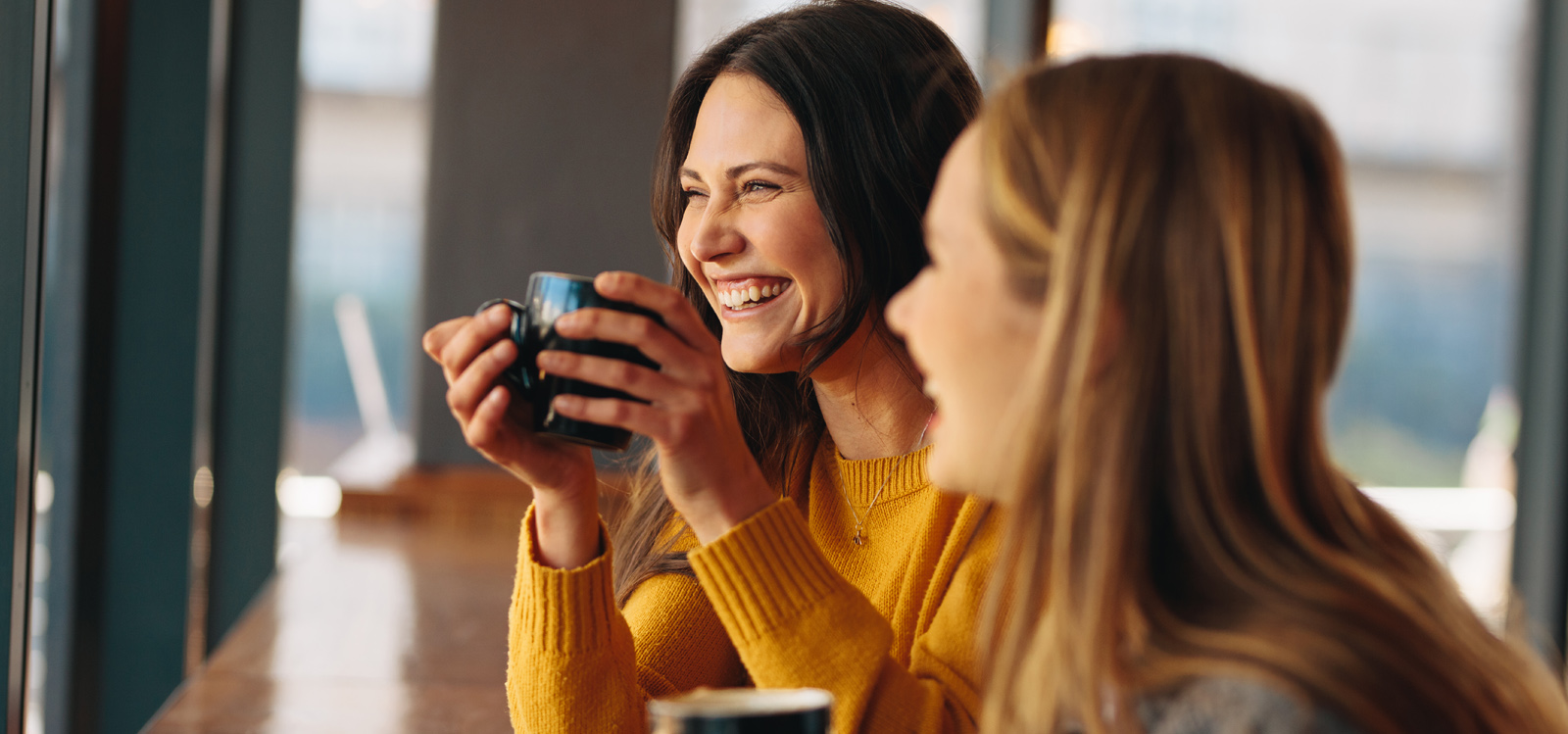 Duas mulheres a beber um copo enquanto se riem Duas mulheres a beber um copo enquanto se riem